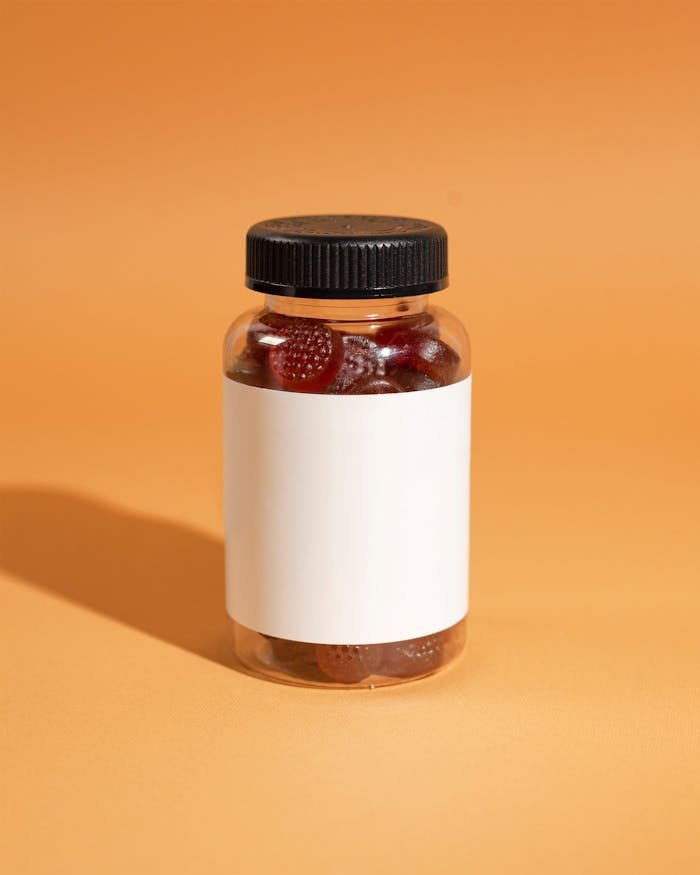 services-03 A clear bottle filled with gummy vitamins on an orange background, ideal for health and wellness themes.
