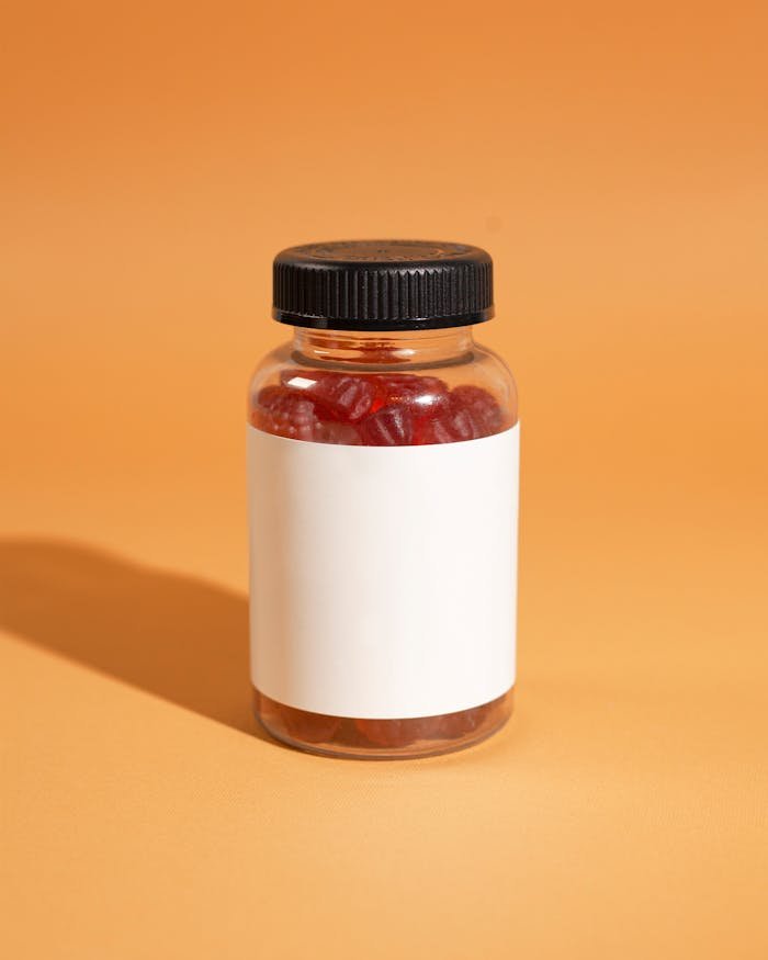 services-01 Clear bottle filled with red gummies on an orange background, perfect for supplement mockups.