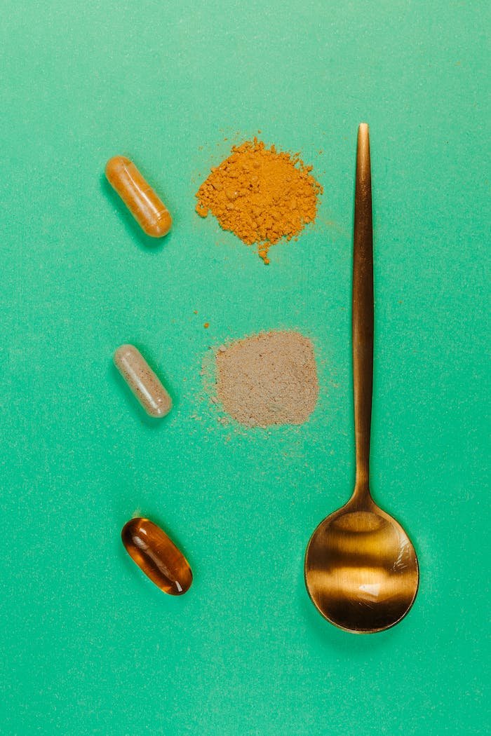 about-03 Top view of a golden spoon with capsules and powders on a vibrant green surface, representing supplements.