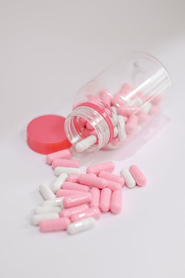 services-05 Close-up of pink and white capsules spilled from a jar, ideal for healthcare themes.