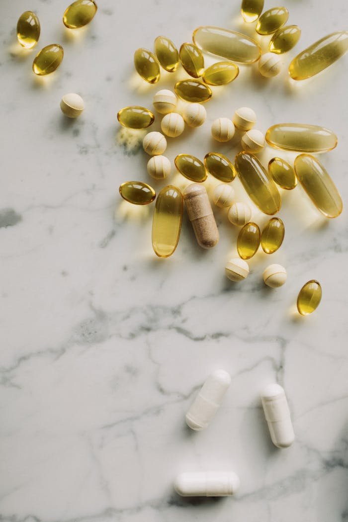 about-01 A collection of various pills and supplements displayed on a marble surface, showcasing healthcare essentials.